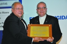 O Reitor Prof. Pe. Josafá Carlos de Siqueira S.J. com o prêmio, ao lado do Reitor da UNIRIO, Luiz Pedro Jutuca. Fotógrafo desconhecido. Acervo do Projeto Comunicar.