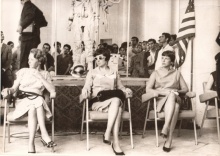 Esposas dos astronautas, com um traje espacial ao fundo.